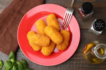 Delicious fried croquettes served on wooden table, flat lay