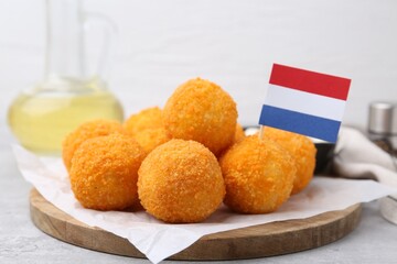 Delicious fried croquette balls and flag of Netherlands on gray table, closeup
