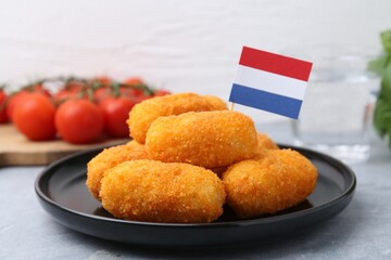 Delicious fried croquettes and flag of Netherlands on gray table, closeup