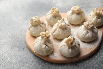 Uncooked khinkalis (dumplings) with flour on grey table