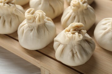 Uncooked khinkalis (dumplings) on white wooden table, closeup