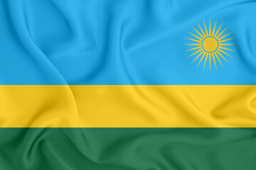 flag of the Republic of Rwanda with three stripes and a yellow sun on satin fabric with folds and...