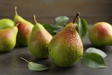 Fresh ripe pears and green leaves on grey table, closeup
