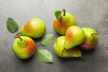 Fresh ripe pears and green leaves on grey table, flat lay