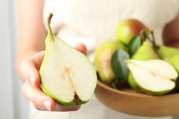 Woman with fresh ripe pears and green leaves indoors, closeup
