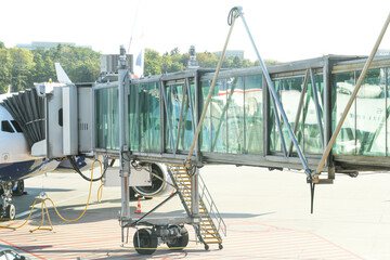 Airport boarding bridge connected to passenger aircraft. Modern glass jetway at terminal gate....