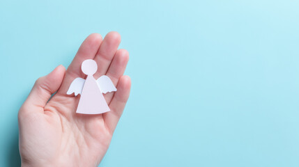 Hand holding white angel symbol on blue background represents miscarriage awareness and gentle emotional support