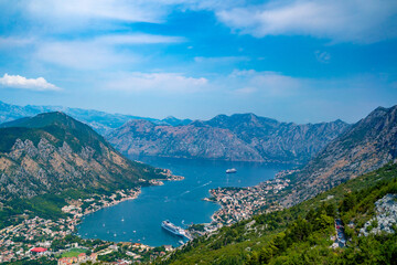 Obraz premium A breathtaking aerial panoramic view of Kotor Bay in Montenegro, featuring a large cruise ship docked in the serene waters surrounded by majestic mountains and a picturesque coastal town