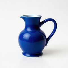 A classic cobalt blue ceramic pitcher with a smooth glossy finish and a graceful handle on a white background