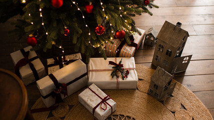 Christmas gift boxes on wooden floor under xmas tree at home. Winter holiday season.
