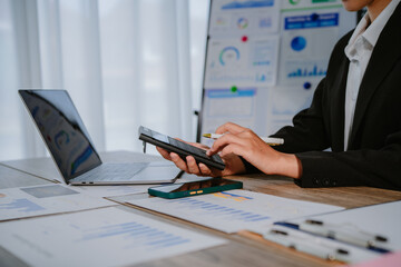 Asian businesswoman using calculator and working on laptop computer at modern office, business and finance concept