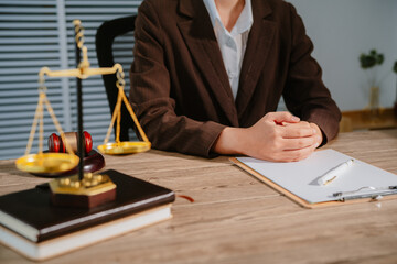 Law office with legal books and scales on table. Legal consultation: lawyer and client reviewing...