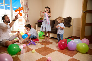 Fototapeta premium A lively family spends quality time together indoors, engaging with colorful balloons and creating joyful memories. The scene reflects love, creativity, and family bonding in a cozy home environment.
