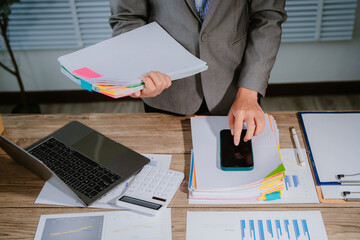 Image of young Asian business woman working working in Stacks of paper files for searching and...