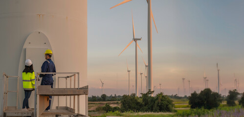 Two engineers working and holding the report at wind turbine farm Power Generator Station on...