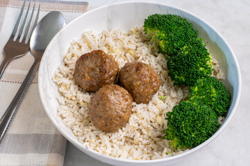 three meat balls served with rice and broccoli