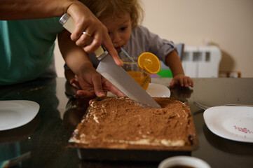 A parent guides their child in cutting a delicious homemade dessert. A warm, intimate moment of...