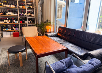 Interior lounge with black sofa, wooden table, and wine shelf. Hospitality, lifestyle, and social...