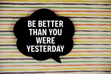 Be Better Than You Were Yesterday text with speech bubble top view on colorful stripes 
background