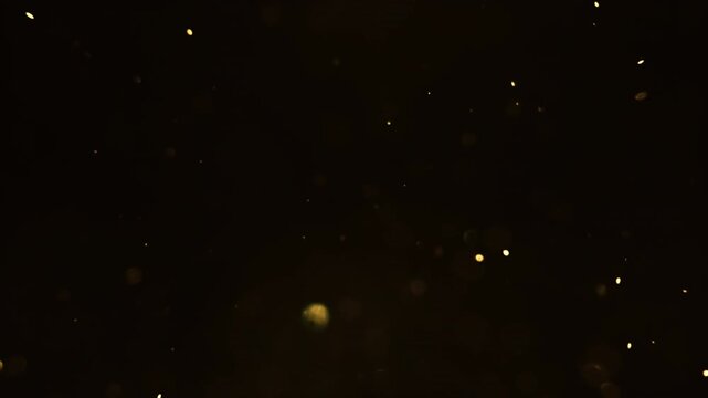 A small yellow fairy dust, snow flying on a black background. 4K slow motion video 60 fps. Beautiful, festive background, template.	