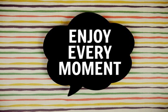 Naklejki Enjoy Every Moment text with speech bubble top view on colorful stripes background