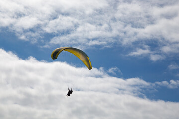 Persone su paracadute giallo e azzurro per parapendio
in cielo con nuvole