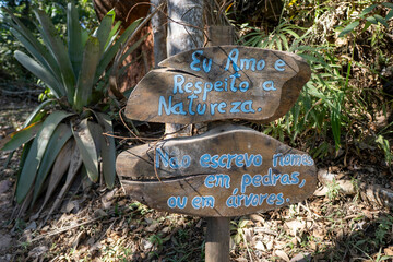 Charming rustic wooden sign in the middle of the forest surrounded by lush greenery