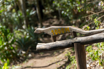 Rustic wooden sign in the forest indicating 1000 meters – hiking trail marker in Brazil