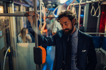 Tired businessman standing on a crowded bus at night