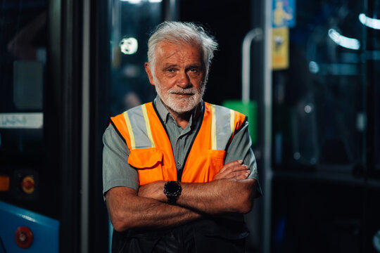 Senior bus driver wearing safety vest posing with crossed arms