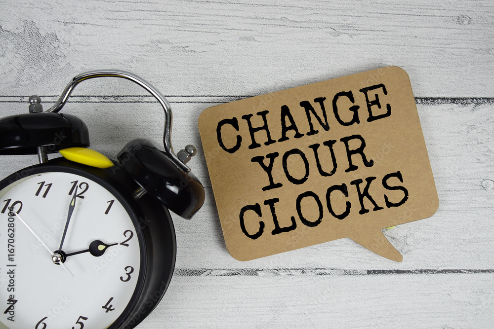 Poster change your clocks text with alarm clock on wooden background