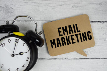 Email marketing text with alarm clock on wooden background