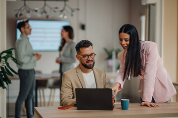 Business colleagues collaborating on laptop in modern office