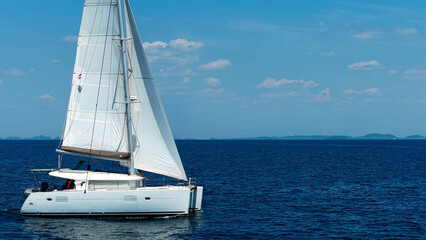 Obraz premium Sailing catamaran with open sails. Sailing catamaran in the middle of the sea in a tropical landscape. Sailing boat with open sails