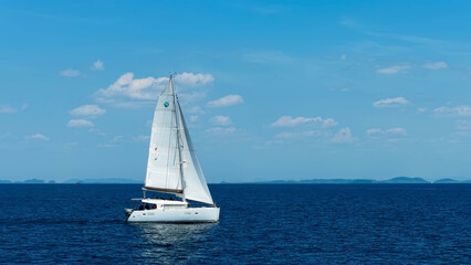Sailing catamaran with open sails.
Sailing catamaran in the middle of the sea in a tropical landscape. Sailing boat with open sails