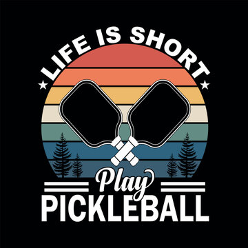 Pickelball Life: A graphic design showcasing a pair of crossed pickleball paddles alongside the optimistic slogan Life is short, play pickleball, perfect for sport