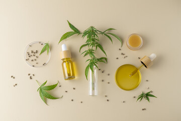 CBD oil from medical hemp seeds in pipette, dropper glass bottle and cannabis leaves on neutral...
