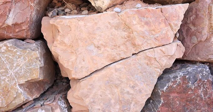 Closeup weathered jagged pink rock cracked and broken in half small stones nearby