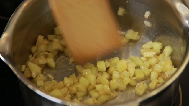 Stirring chopped apples with cinnamon in a saucepan for the filling of pita sandwich