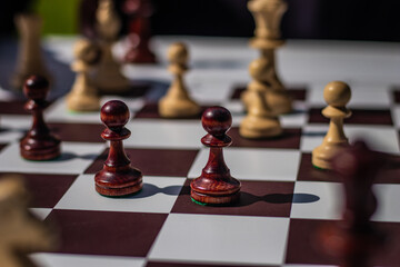 Two dark wooden pawns in focus during an intense chess game, symbolizing strategy, competition, and...