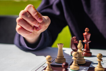 Close-up of a person's hand about to move a chess piece on a board, representing focus,...
