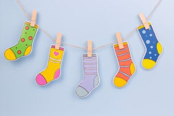 Colorful mismatched socks hanging on line over neutral light blue background. Down Syndrome...