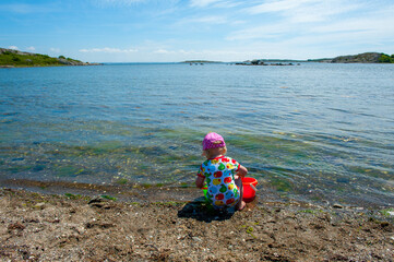 Young child playing at peaceful rocky shoreline.
