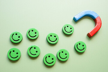 Magnet attracting smiley faces. Customer engagement and positive energy.