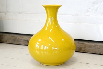 A tall bright yellow ceramic vase with a glossy finish and elegant shape