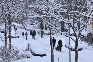 some families enjoys a peaceful winter day on a snow-covered street in MÃ¼nster, Germany, pulling...