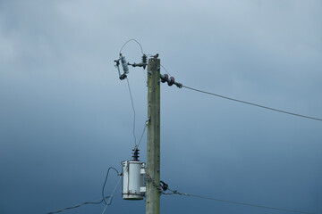 Utility pole with transformer and wires set against a cloudy, overcast sky