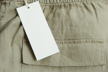 Mockup. Linen pants with blank white paper price tag. Clothing label tag card with copy space for...