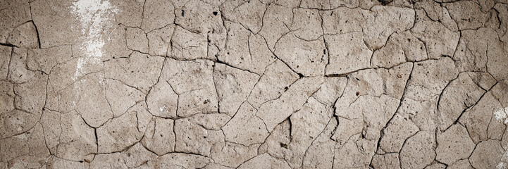 Concrete wall texture with cracked plaster. Weathered rough surface. Panoramic background for grunge design.