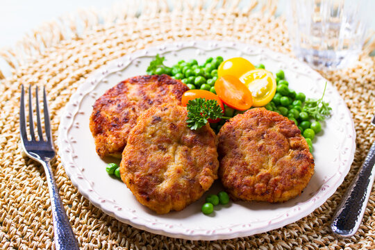 Fish burgers with vegetables on white plate. Fish patties or cakes